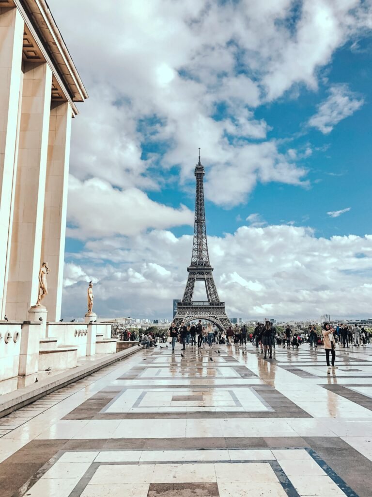 A scenic view of the Eiffel Tower in Paris with tourists on a sunny day. Captured from Trocadéro plaza.